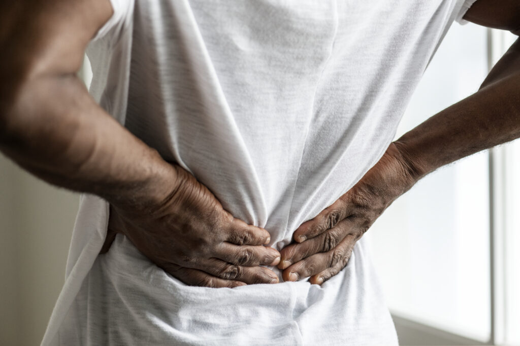 Person in a white shirt clasps their hands at the abdomen, arms crossed in front of the stomach.